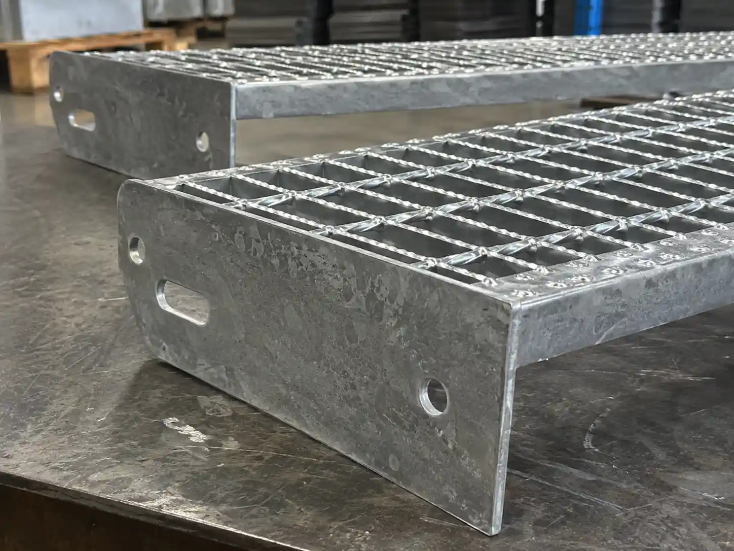 Close-up of bar grating stair tread end plates with prepared mounting holes for bolted stair installation